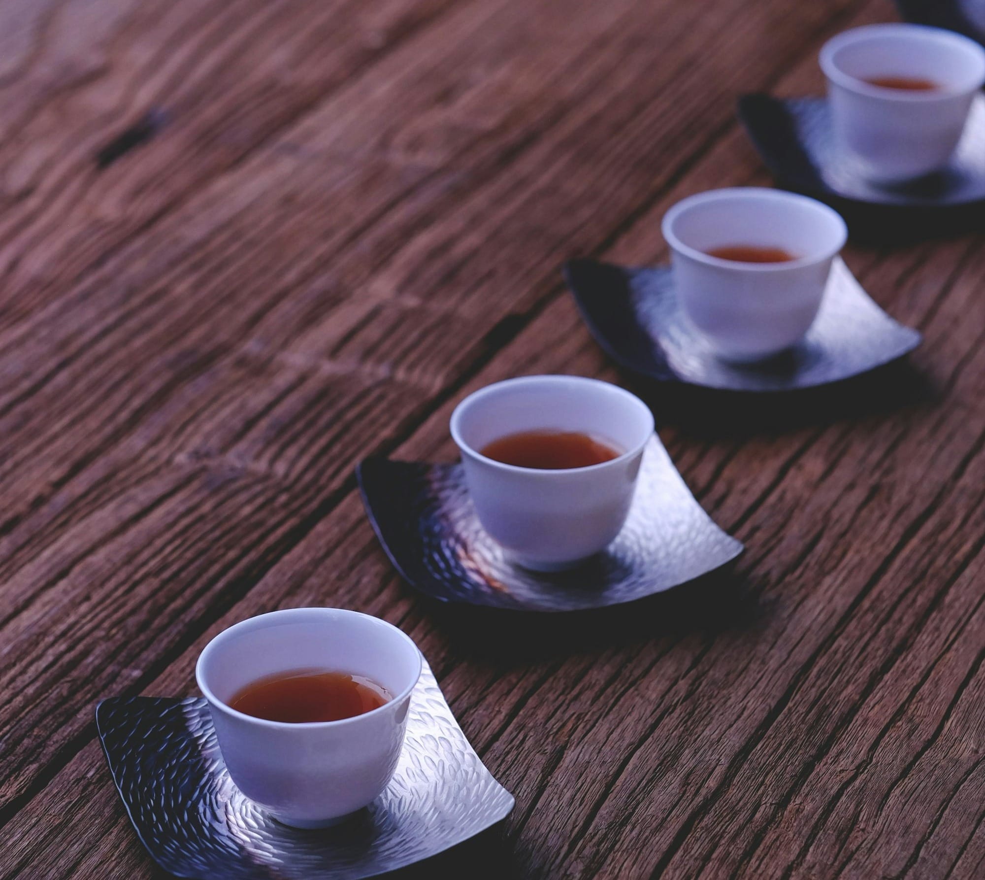 inline white ceramic bowls filled with brown liquids on brown wooden table