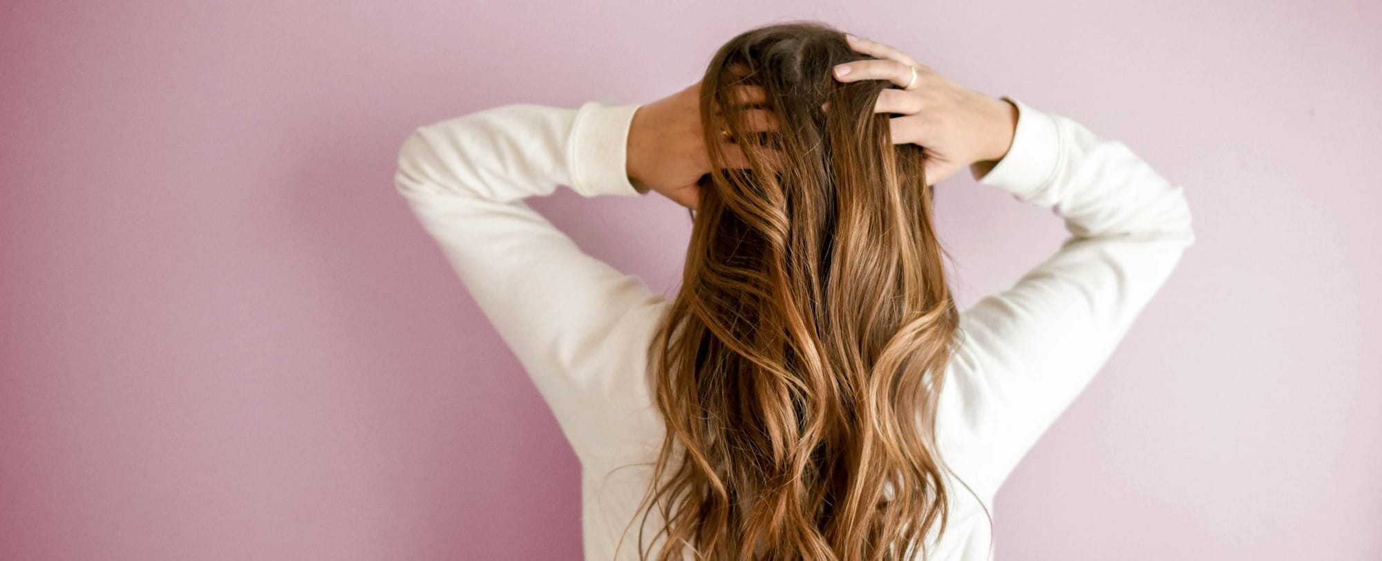 woman in white long-sleeved shirt standing in front of pink wall